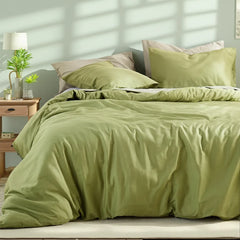 Front view of a matcha green duvet on a bed with light and dark pillows, highlighted by striped sunlight shadows on the wall.