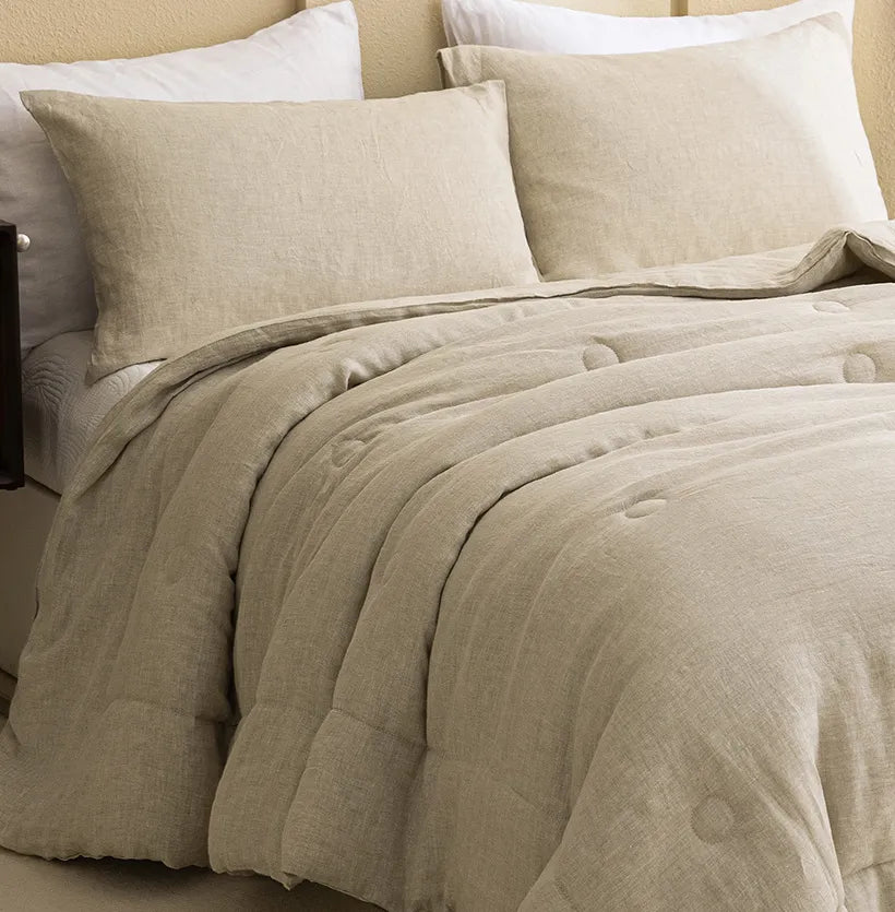 Pair of natural french linen pillowcases styled on a bed with a comforter