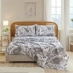 Close up view of cotton neutral paisley sheet set on bed with rustic rattan headboard