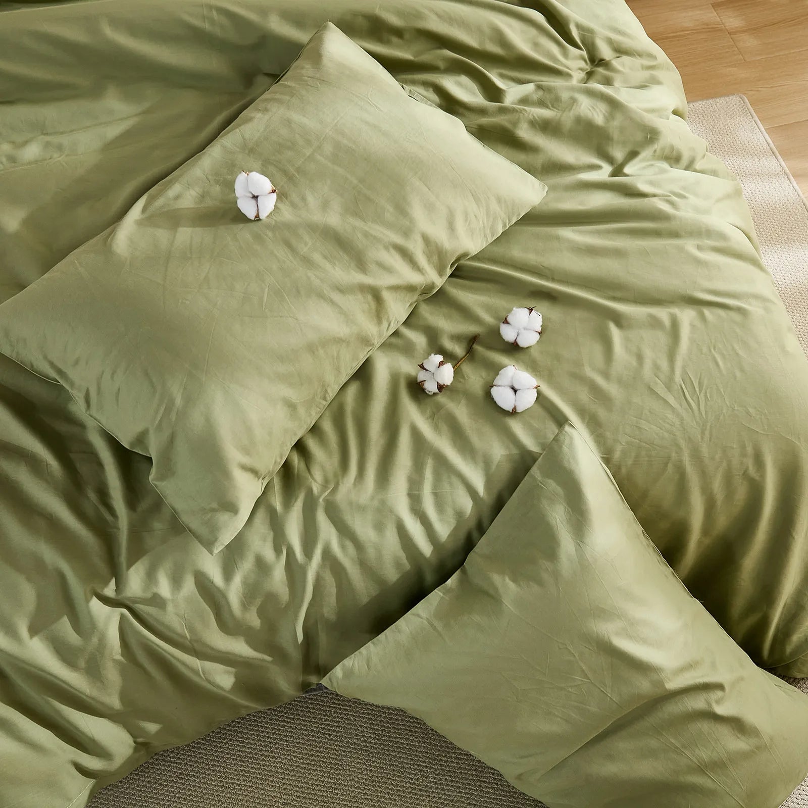 Olive green duvet cover with four cotton clusters and three pillows arrangement