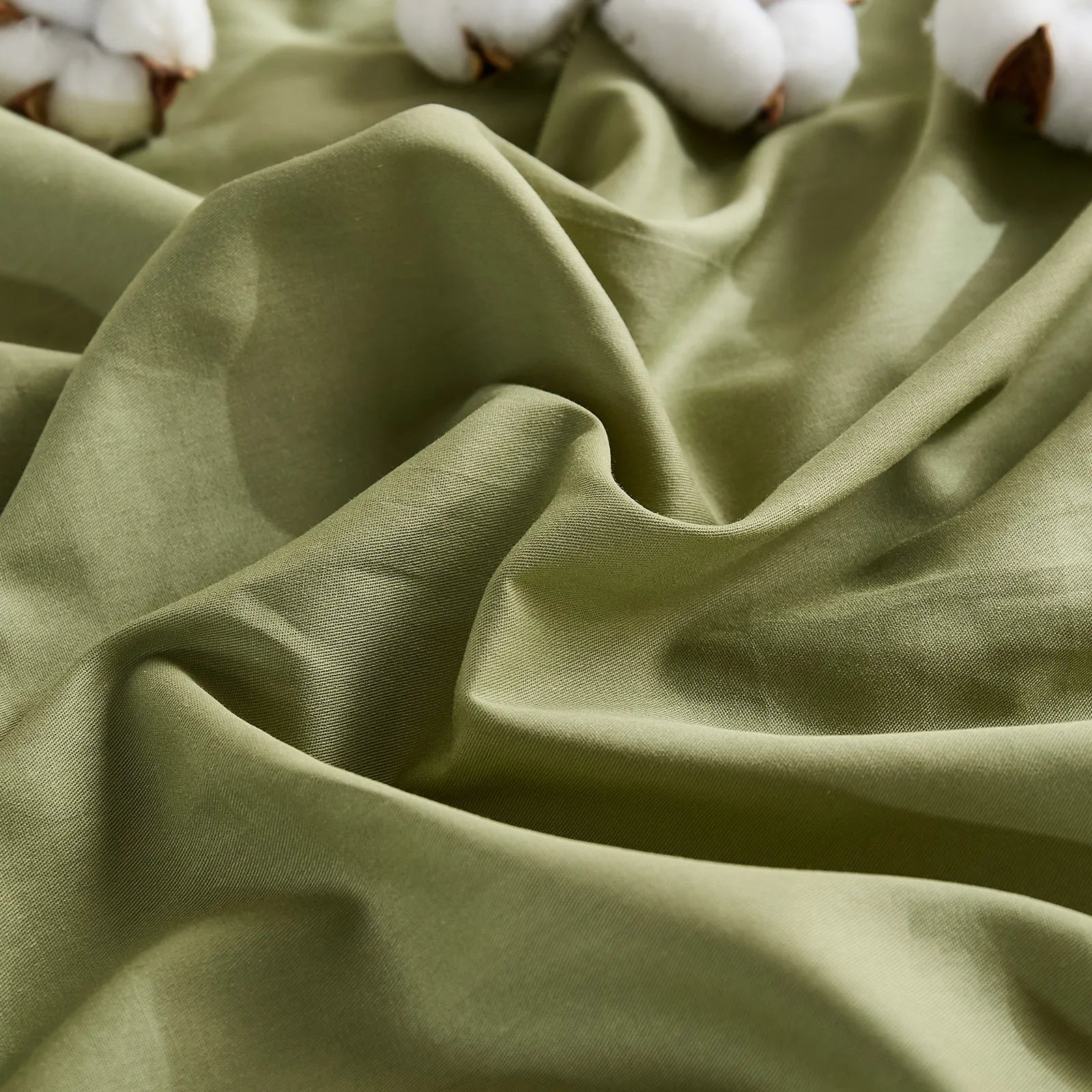 Olive green duvet cover with two cotton buds on wrinkled fabric, front view