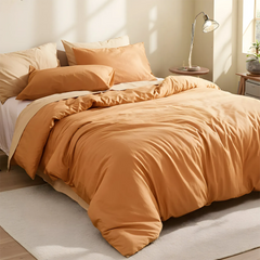 Angled view of orange duvet with pillow arrangement on bed.