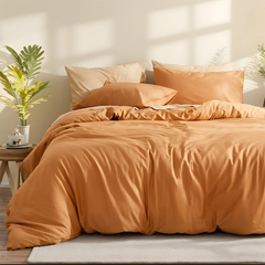 Close-up of orange duvet neatly spread on bed with pillows.