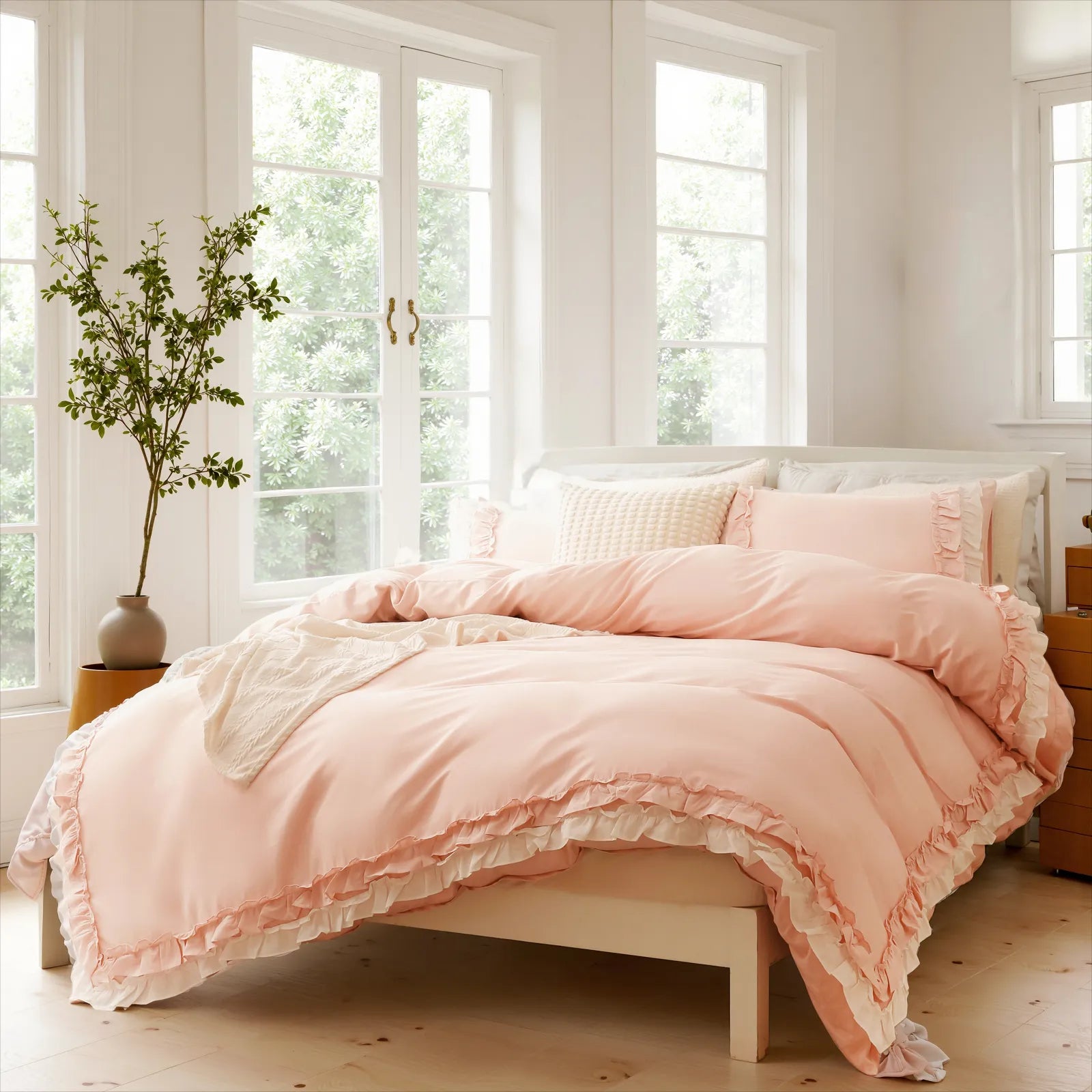 Light pink cotton double ruffle duvet cover on a bed, with decorative pillows, near large windows.