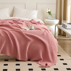 Pink Knitted Throw Blanket with Tassels Draped on Bed