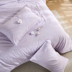 Purple solid duvet on bed with four cotton blooms and two pillows arrangement