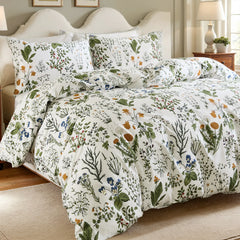 A close-up, angled view of a white comforter and pillows with a detailed botanical and floral print.