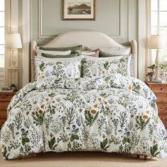 A styled bed with a white comforter and pillows with a botanical print and a green border, framed by a rattan headboard.