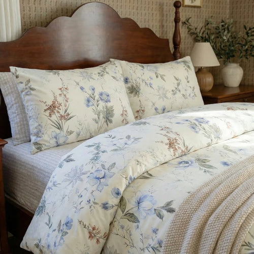 close-up of blue floral cotton bedding with warm bedside lamp and vintage wood furniture