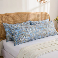 A pair of long blue paisley print cotton body pillows placed together on a bed, with a white blanket draped across the front.