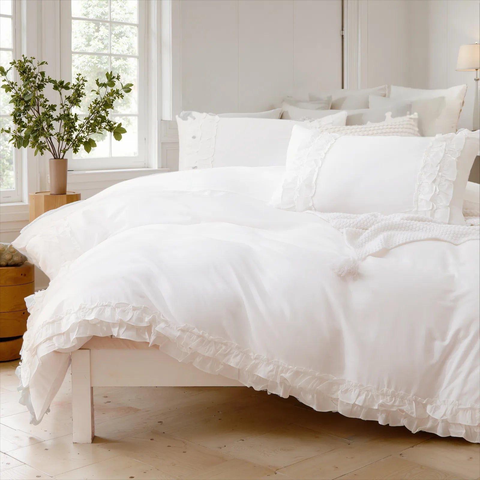 Close-up view of a soft white cotton ruffle duvet cover and a stack of pillows on the bed.