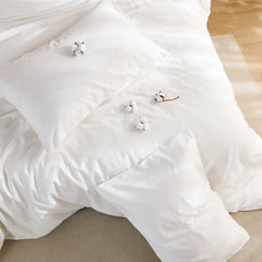 White solid duvet layout with four cotton blooms and two pillows