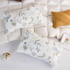 Overhead view of two cotton pillowcases with the blue floral print on a white quilted down comforter.