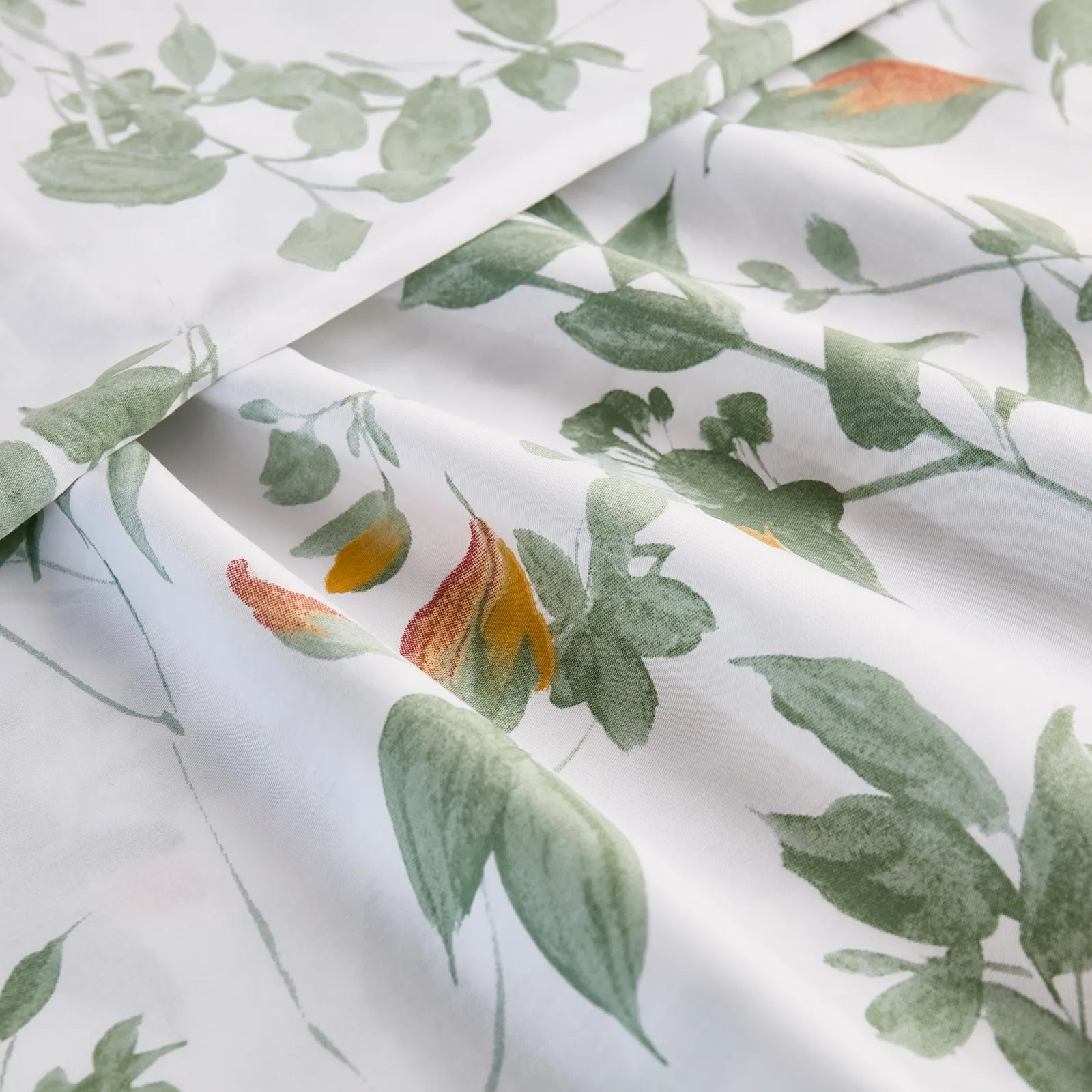 Extreme close-up of the cotton fabric, showing the texture and the detailed watercolor-style green and yellow leaf pattern.