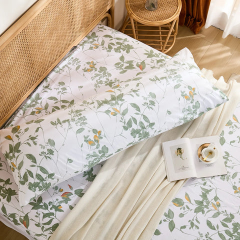 High-angle overhead shot of the long cotton body pillowcase and matching fitted sheet set with green leaf print.