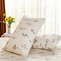 Two cotton pillowcases with a botanical wildflower print, brightly lit by a window with sheer white curtains.