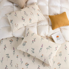Overhead view of two cotton pillowcases and a fitted sheet with the wildflower print on a white down comforter.