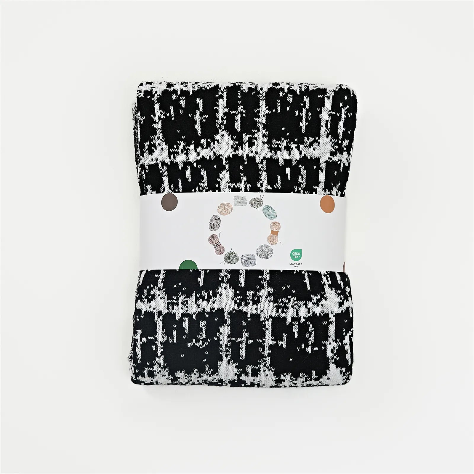 A neatly folded and packaged artistic black and white wool blanket, ready for retail.