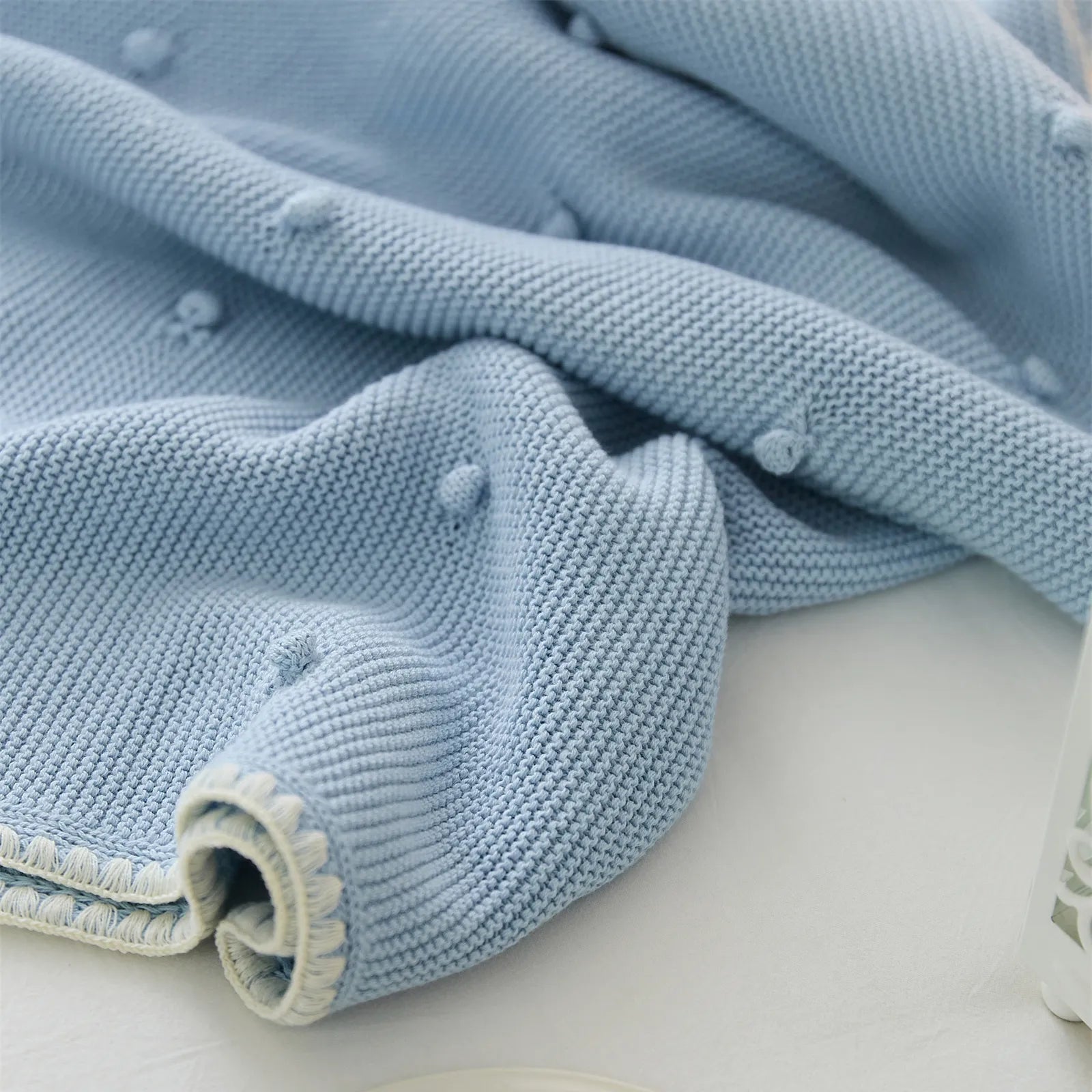 Close up detail of soft baby blue cotton knit fabric showing bobble texture and soft folds