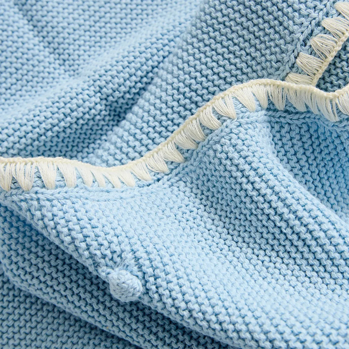 Close up of the baby blue cotton throw edge showing the cream contrast decorative fringe trim