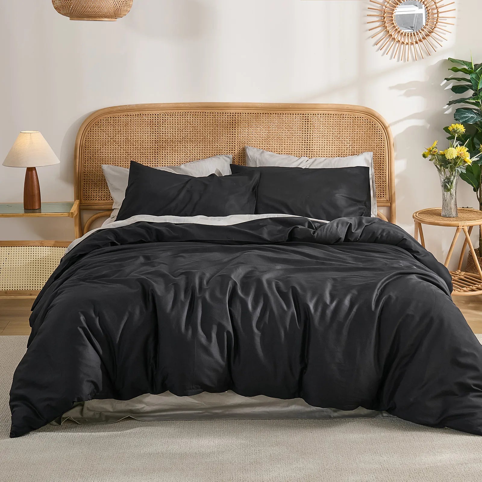 Symmetric bedroom layout with black duvet centered between two woven side tables, circular wall mirror above.