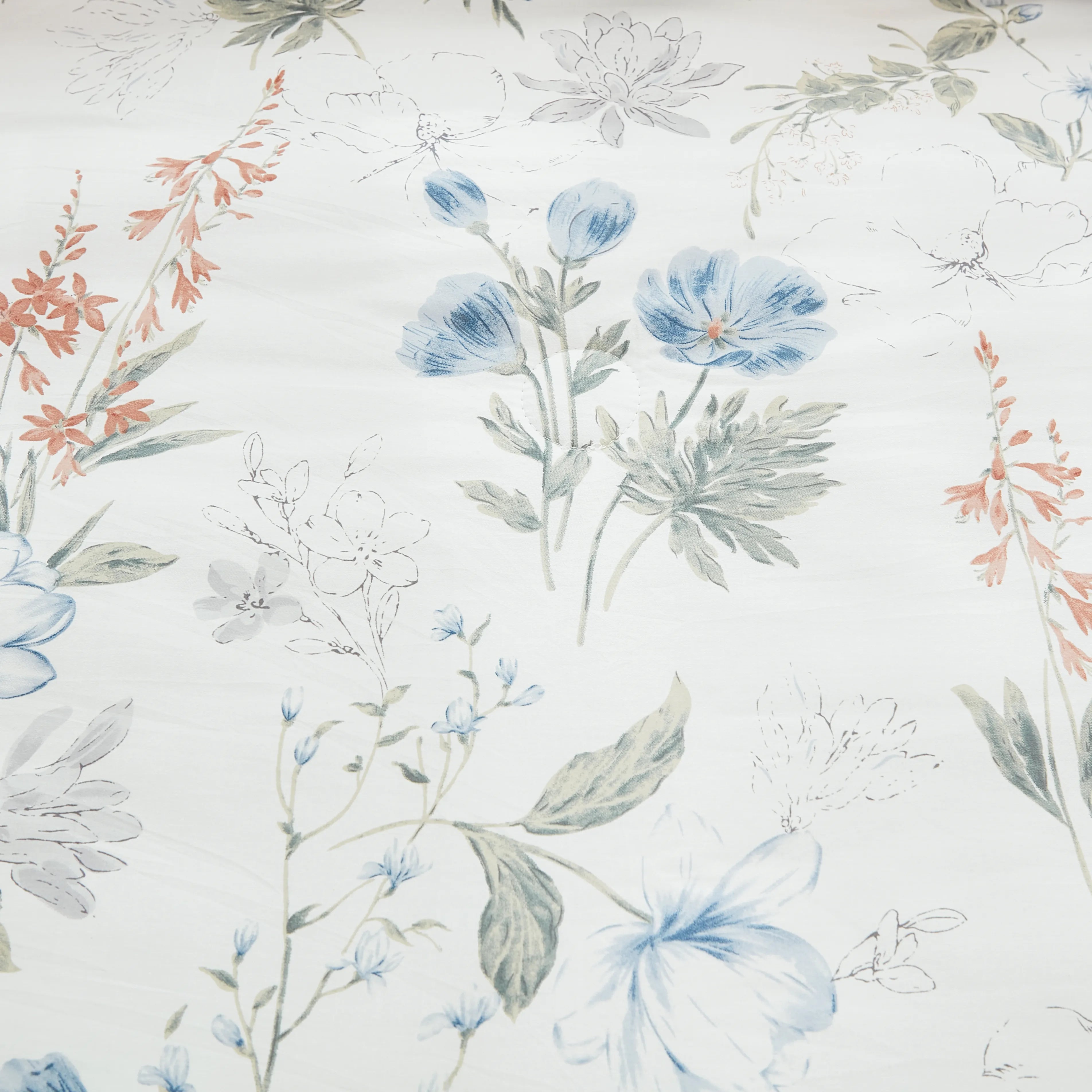 Close-up of the blue and orange floral pattern on a white fabric background.