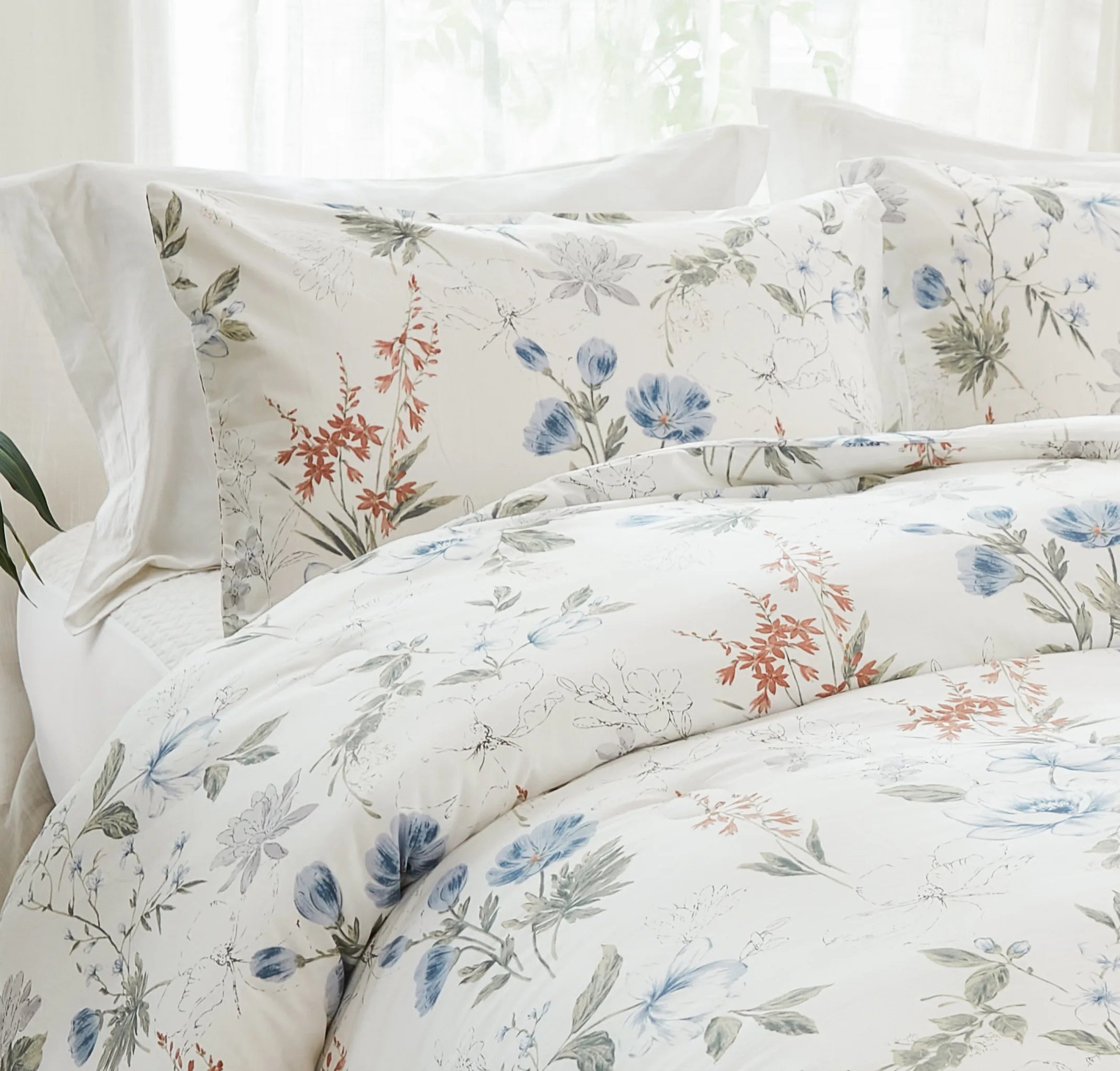 The blue floral comforter set styled in a cozy, bright bedroom.