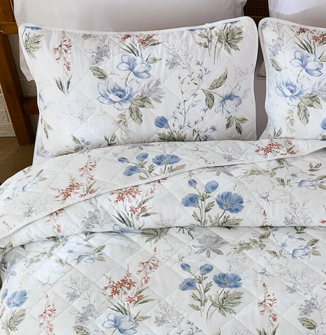 Overhead view of the quilt and pillowcases, highlighting the quilted texture and detailed floral design