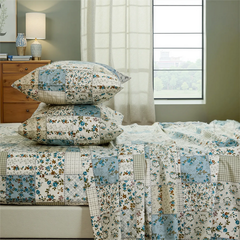 Stacked blue and green floral patchwork cotton pillows on the fitted sheet set close up	
