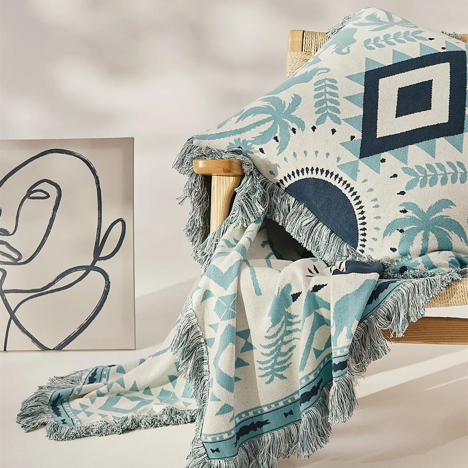 A cozy blue bohemian cotton blanket with tassels, draped stylishly over a light-colored armchair