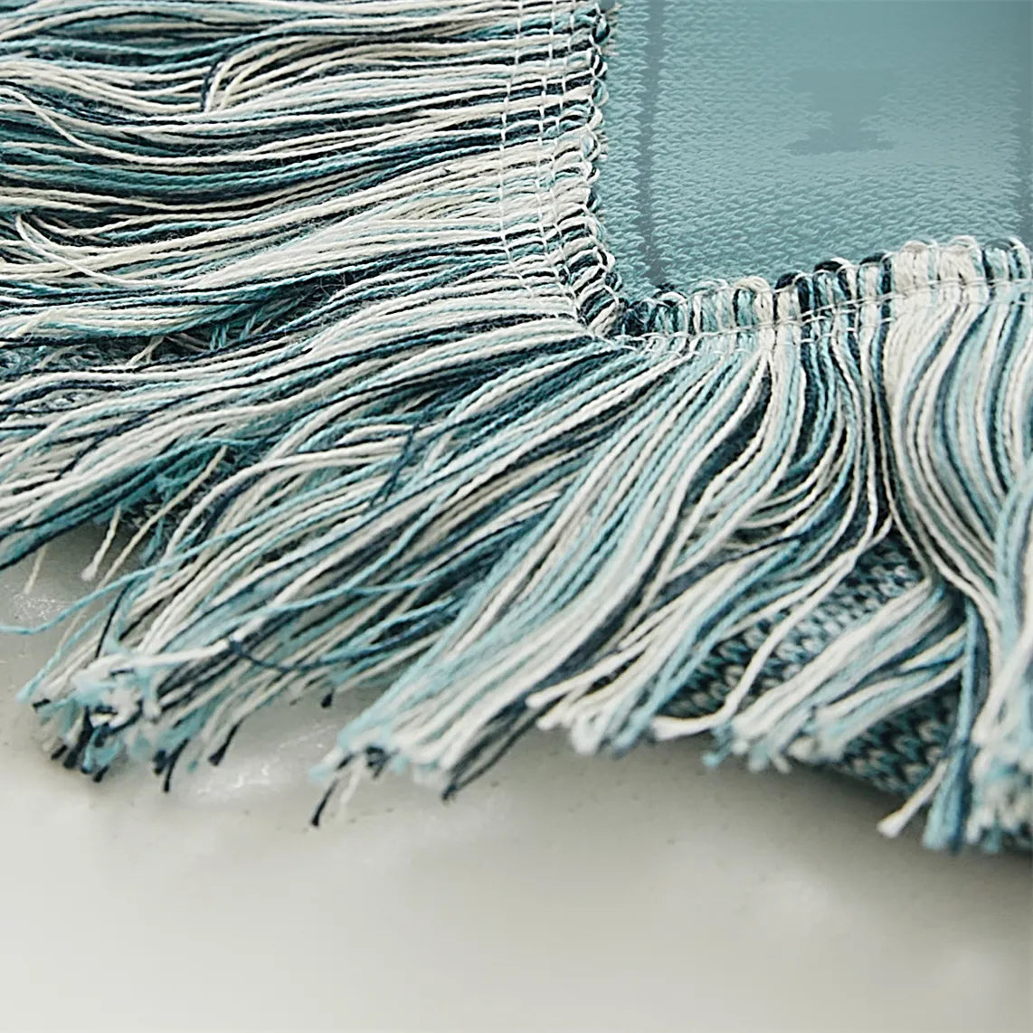 detailed shot of the soft, patterned cotton fabric and decorative tassels of the blue bohemian blanket.