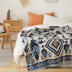 A boho-inspired leaf pattern fleece blanket spread out on a white bed, with tassels for a decorative touch.