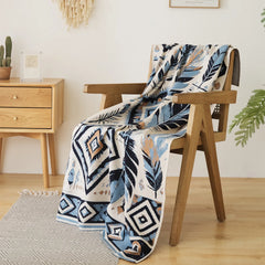 The leaf pattern fleece blanket is draped over a wooden chair, showcasing its elegant design and soft texture.