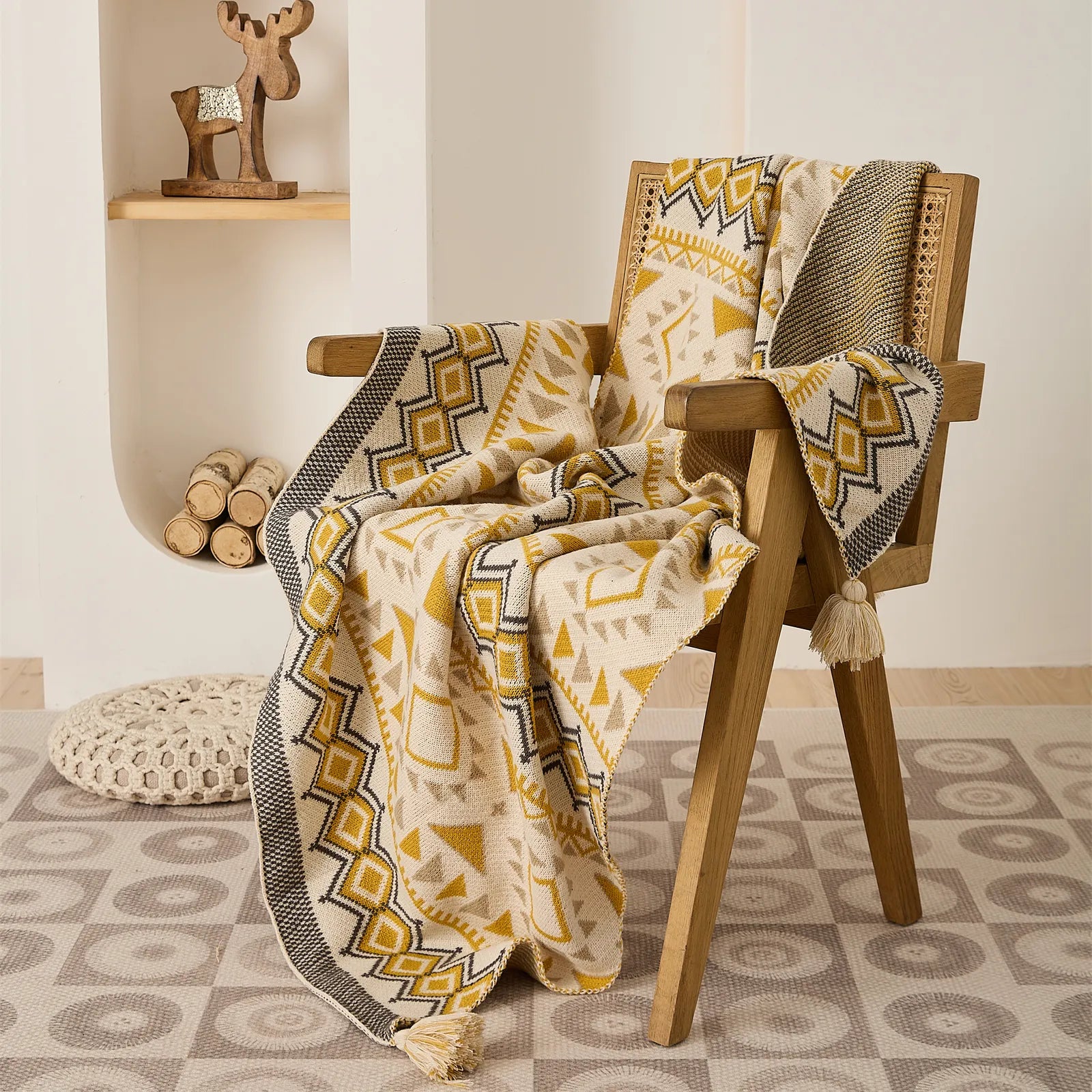 Boho geometric knit throw blanket in mustard yellow draped on a wooden rattan chair