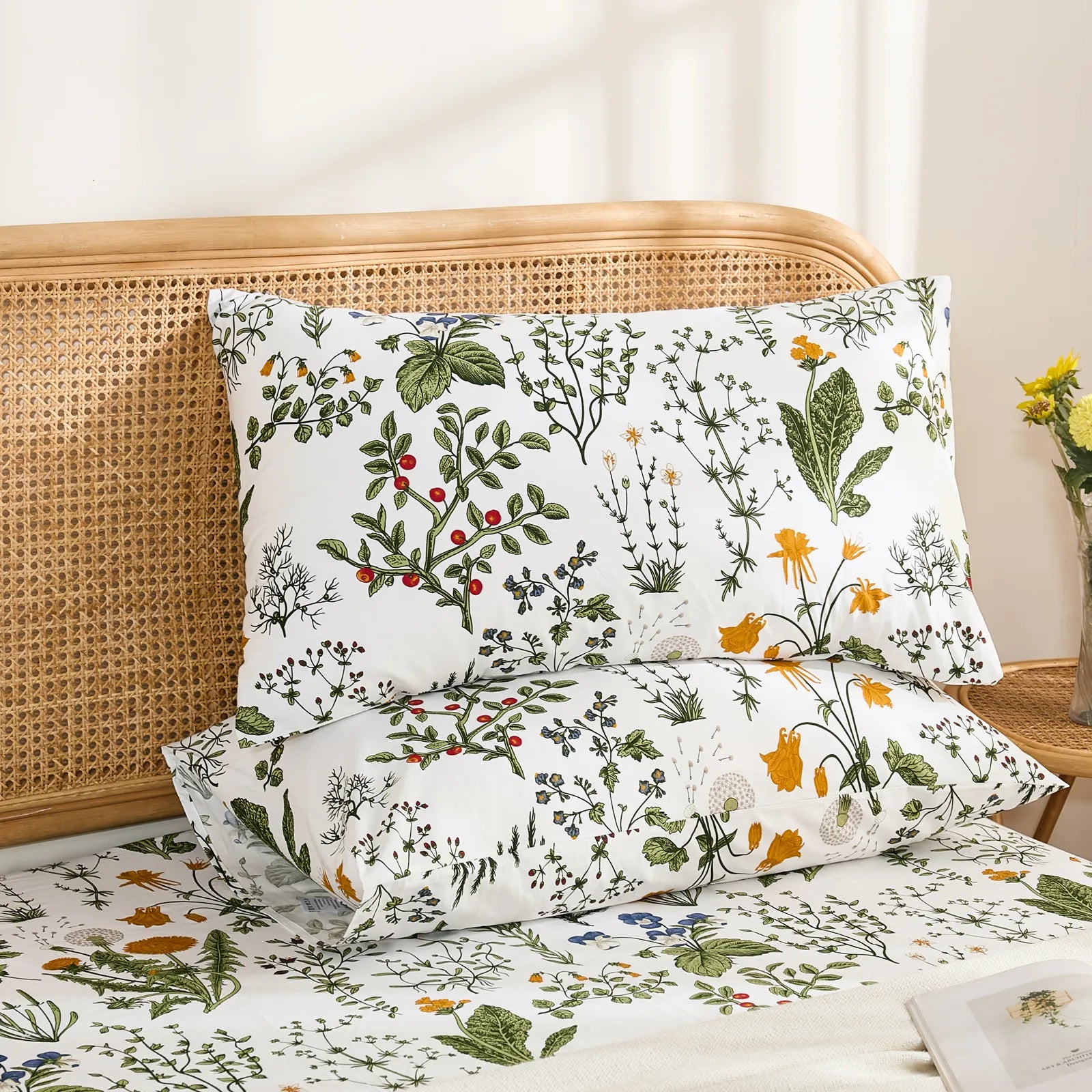 Two white cotton pillowcases with a detailed botanical pattern, stacked on top of each other, showcasing the vibrant floral and plant design.