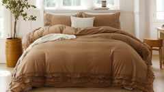 Brown cotton double ruffle duvet cover set with a white pillow, beside a cylindrical planter and a white lamp on a wooden stool.