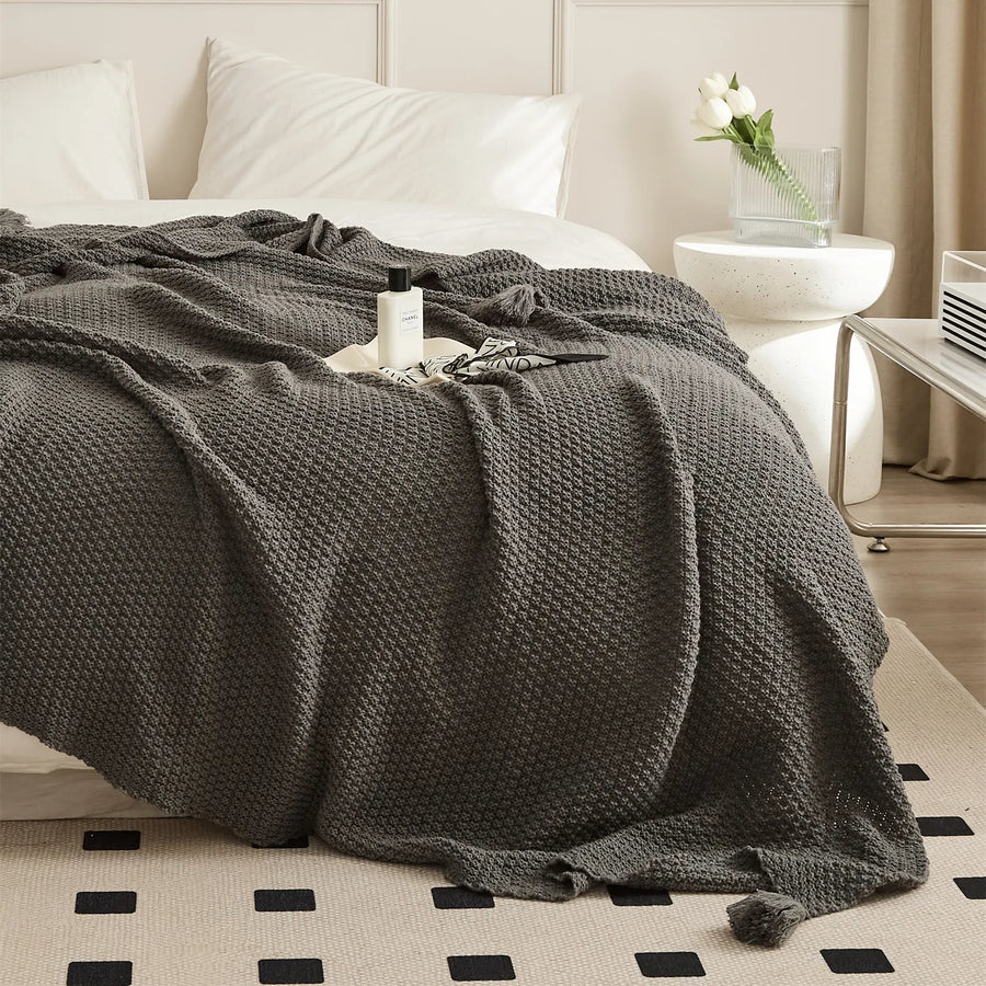 Charcoal Knitted Throw Blanket Draped Bedside with Perfume Bottle