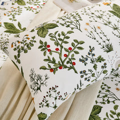 A close-up view of a white cotton pillowcase, highlighting the detailed botanical pattern with red berries, leaves, and various small flowers.