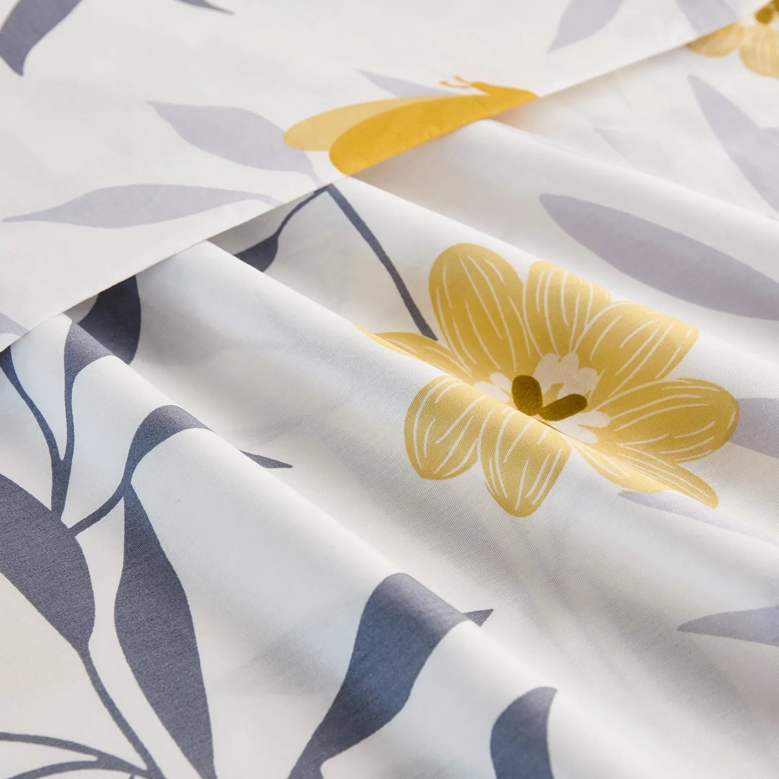 A close-up of the folded white cotton fabric, highlighting the crisp, modern print of a yellow flower and grey leaves.
