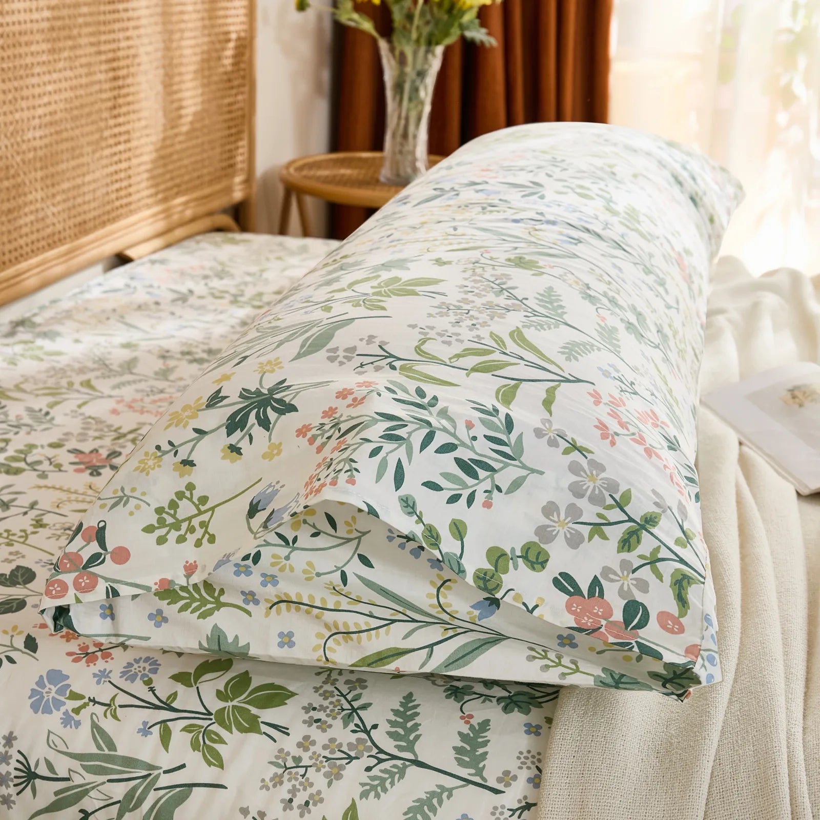  A side-angled view of a cotton wildflower body pillowcase on a bed, showing the end of the pillowcase and the matching patterned bedding.