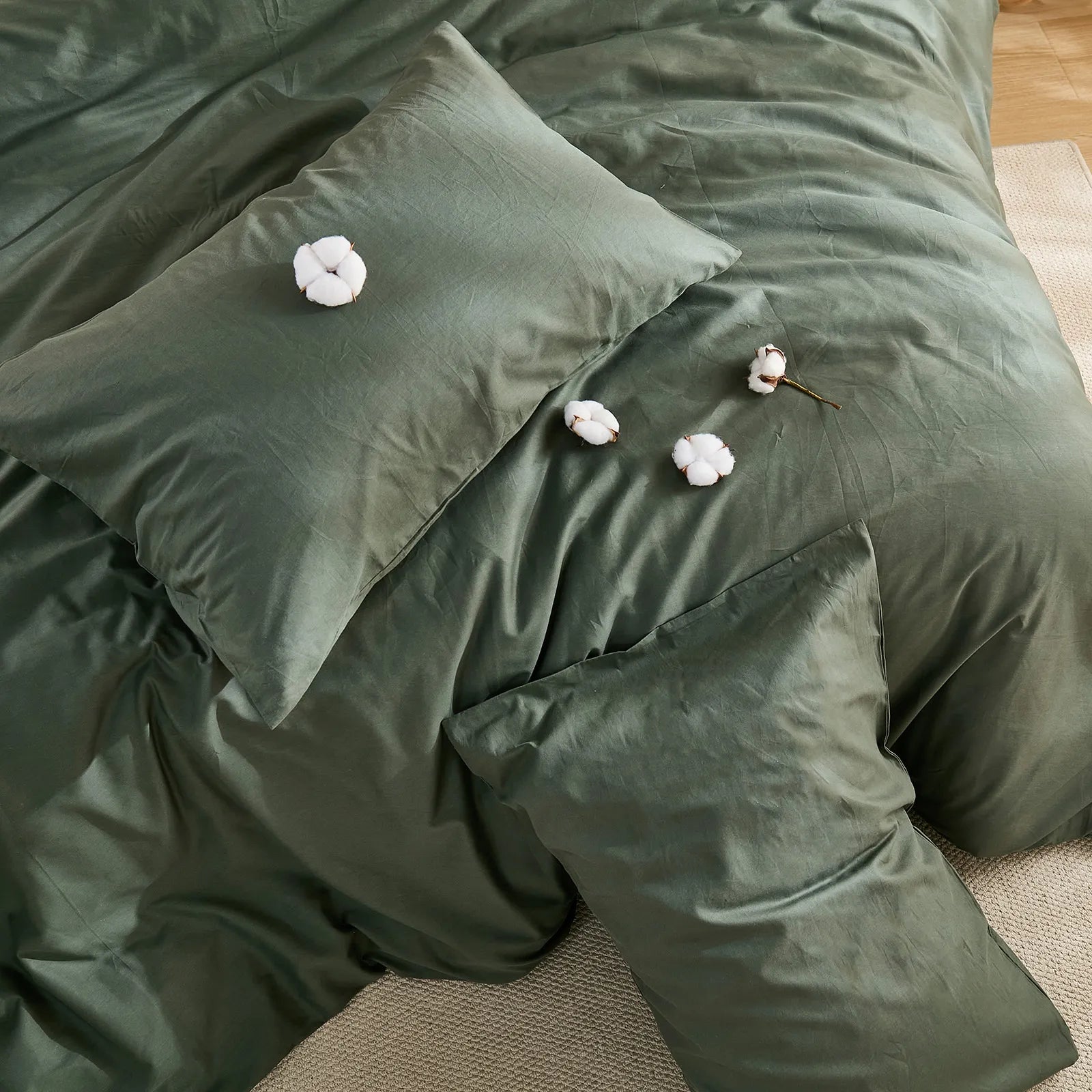 Dark green duvet cover with four cotton clusters and three pillows arrangement