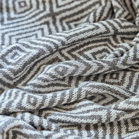 Detailed close-up of the charcoal-grey diamond knit throw's weave, highlighting the two-tone geometric pattern.