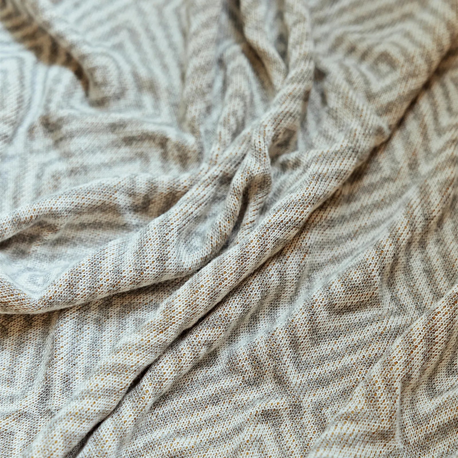 Detailed close-up of the light-grey diamond knit throw's weave, highlighting the two-tone texture and knotting.
