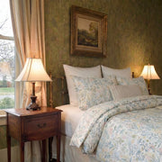 wide side angle of colorful wildflower duvet cover set in a bright bedroom with antique furniture