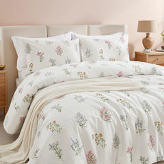  Close-up of a bed with a white comforter and pillows featuring a charming pastel floral pattern.
