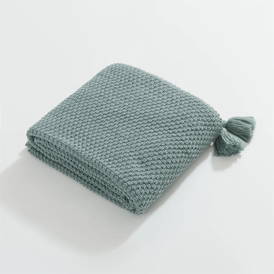 Folded Aqua Knitted Throw Blanket on White Background Showing Tassel