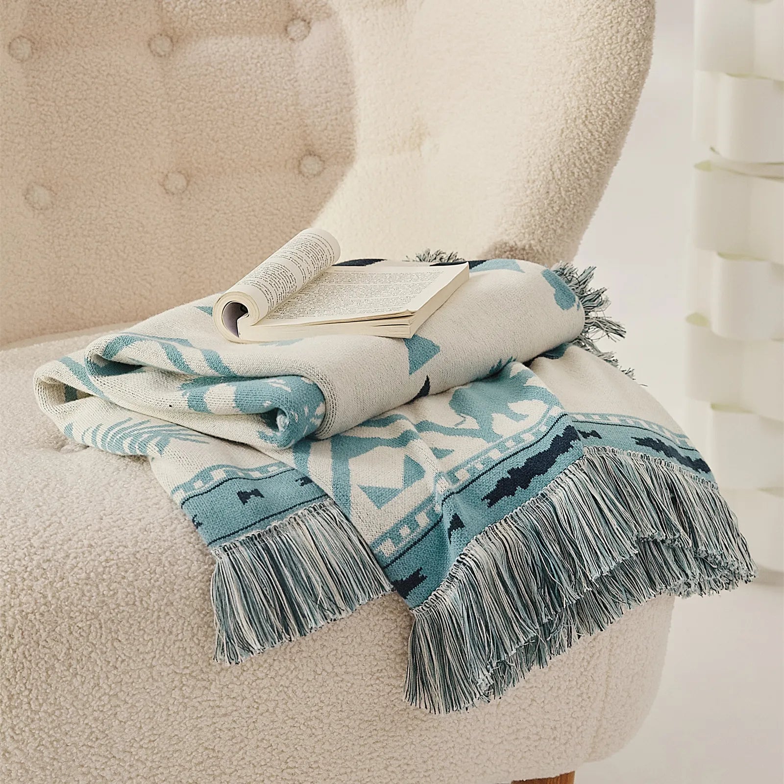 A neatly folded Prussian blue bohemian tassel blanket, ready to use as a cozy throw or decorative accent