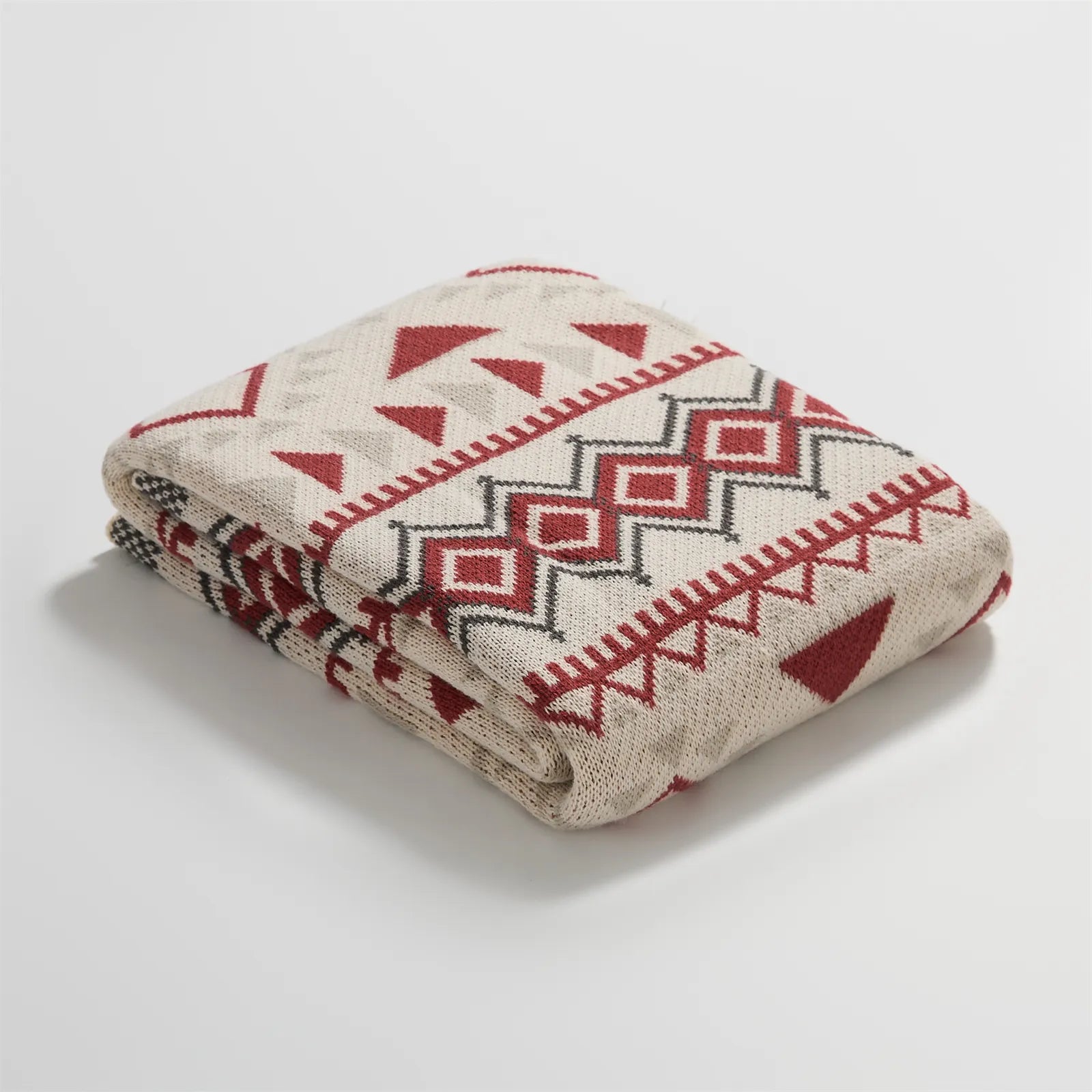 Neatly folded red cream and gray boho geometric knit blanket studio shot