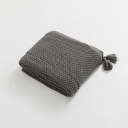 Folded Charcoal Knitted Throw Blanket Showing Tassel on White Background