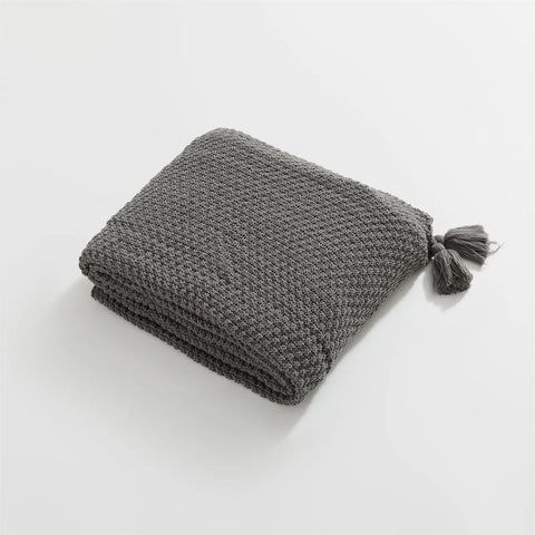 Folded Charcoal Knitted Throw Blanket Showing Tassel on White Background